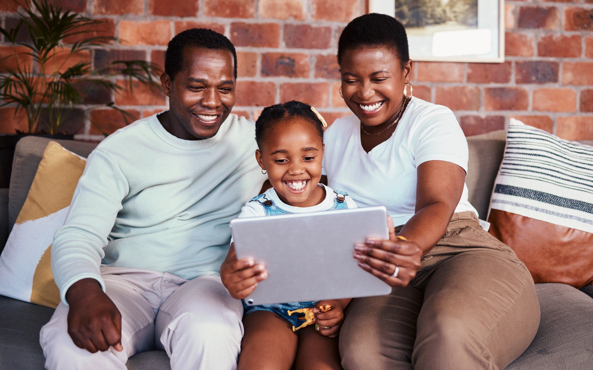 Family, tablet and child with internet on a home sofa for e learning, bonding and time together. Happy man, woman and girl kid in a lounge with technology for education, online game or to watch movie